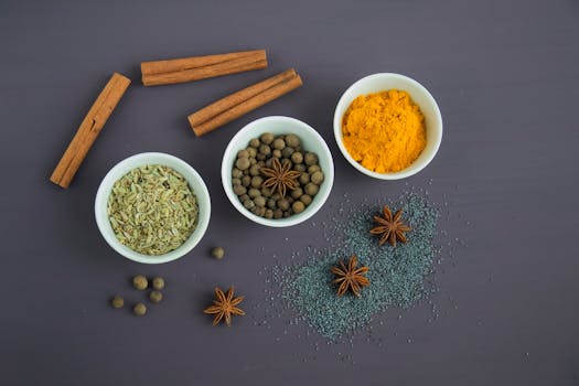 Flat lay of assorted spices including cinnamon, turmeric, and star anise on a dark surface.
